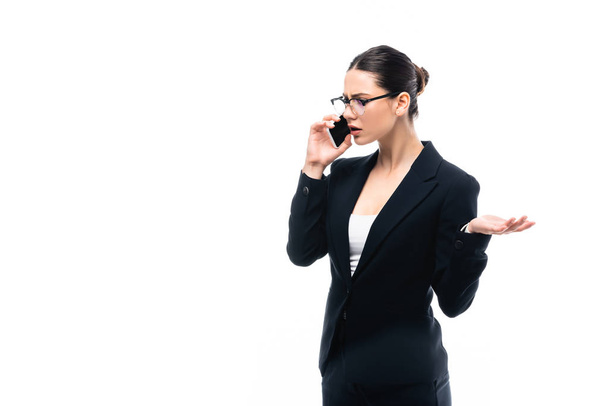 dissatisfied businesswoman gesturing while talking on smartphone isolated on white - Fotografie, Obrázek