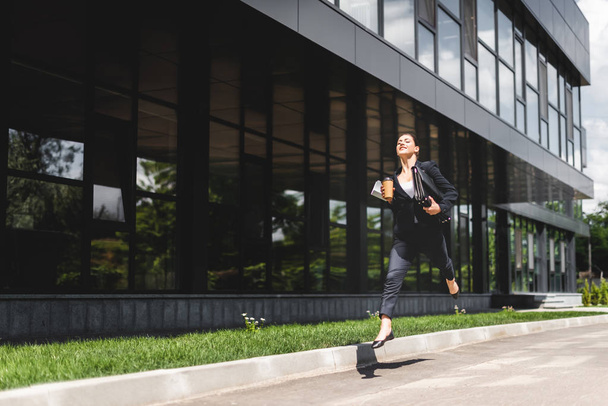 happy businesswoman levitating while holding briefcase and coffee to go  - Photo, Image