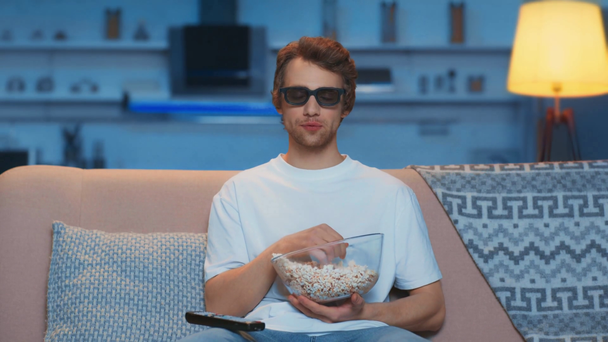 lachende man in 3D-bril die popcorn eet en TV kijkt - Video