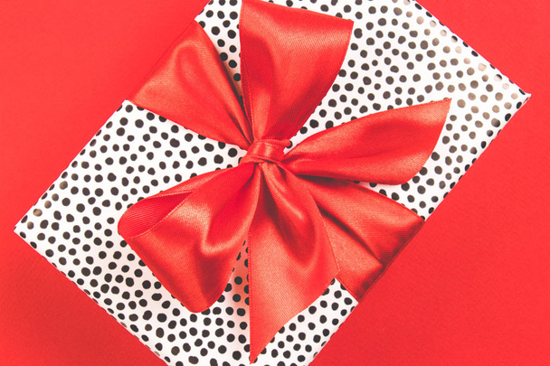 Caja de regalo con lazo de satén rojo sobre fondo rojo. Concepto festivo. Vista superior
. - Foto, imagen