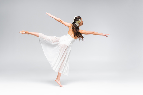 schöne, elegante Ballerina im weißen Kleid, die auf grauem Hintergrund tanzt - Foto, Bild