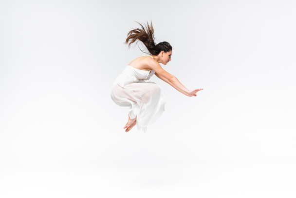 vista lateral da bela bailarina jovem pulando enquanto dança em fundo cinza
 - Foto, Imagem