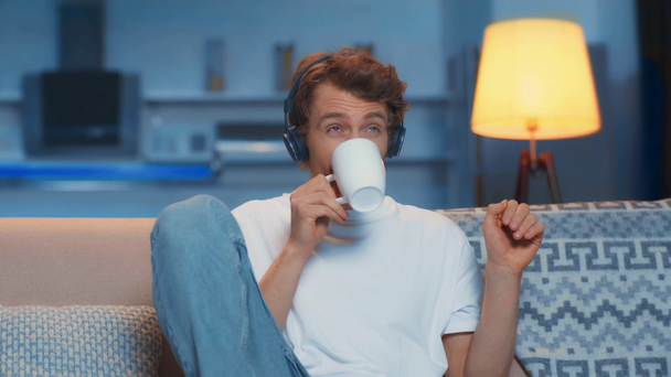 ember hallgat zenét, teát iszik és énekel a kanapén - Felvétel, videó