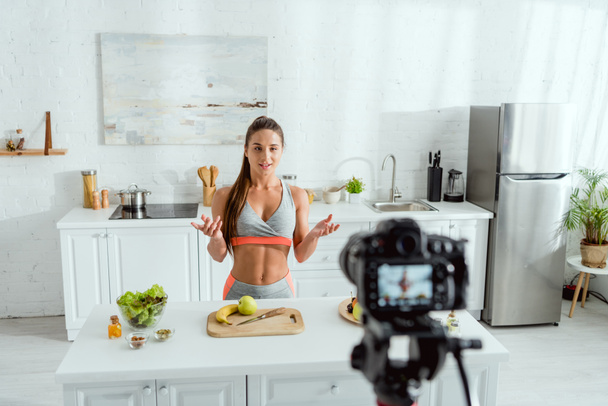 επιλεκτική εστίαση του ελκυστικού blogger βίντεο κοντά στα φρούτα και την ψηφιακή φωτογραφική μηχανή  - Φωτογραφία, εικόνα
