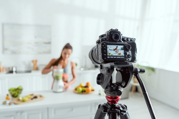 селективный фокус цифровой камеры с веселой женщиной, готовящей смузи в блендере на экране
  - Фото, изображение