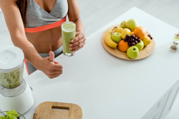 cropped view of woman showing thumb up while holding glass with smoothie  - Foto, imagen