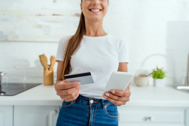 selective focus of cheerful woman holding smartphone and credit card  - Photo, Image