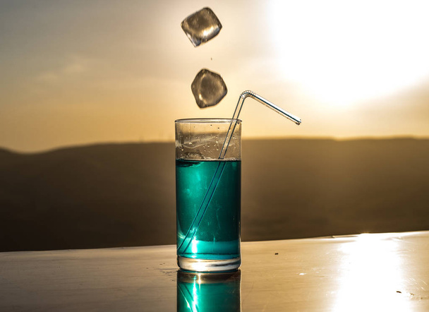 Conceito de bebida refrescante de verão. Óculos de cocktail a salpicar ao pôr-do-sol. Close up copo molhado de bebida fria no terraço
. - Foto, Imagem