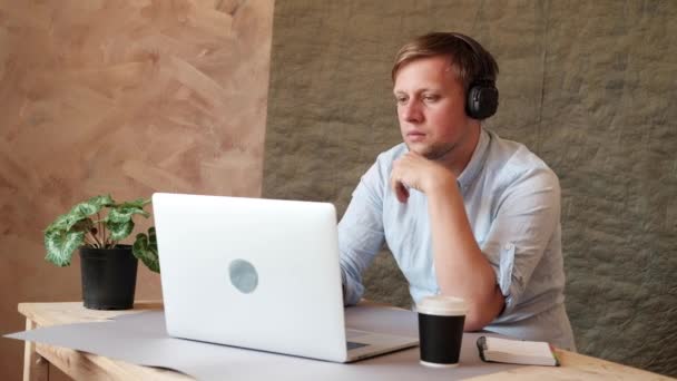 Man typing on laptop keyboard, listening to music in headphones and drinking coffee. reelance, coworking, business, office - Materiał filmowy, wideo
