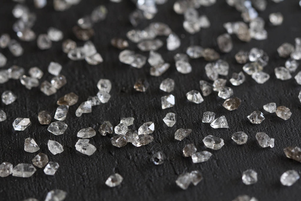 Scattered diamonds on a black background. Raw diamonds and minin - Фото, изображение
