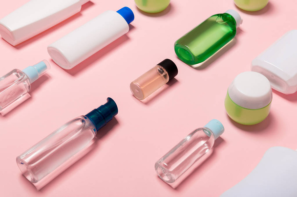 Pohled na kosmetické nádoby, rozprašovače, sklenice a láhve na růžovém pozadí. Zobrazení zavřením s prázdným místem pro návrh - Fotografie, Obrázek
