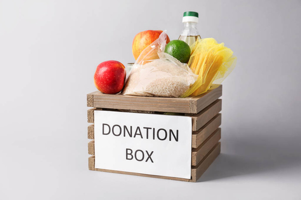 Box with donation food on grey background - Photo, Image