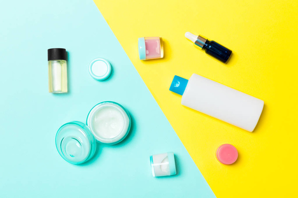 Top view of cosmetic containers, sprays, jars and bottles on yellow and blue background. Close-up view with empty space for your design - Photo, Image