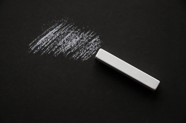 Ένα κομμάτι Λευκή κιμωλία σε μαύρο χαρτί με επίστρωση - Φωτογραφία, εικόνα