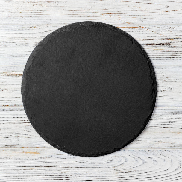 Placa redonda negra sobre fondo de madera, vista superior, espacio para copiar
 - Foto, Imagen