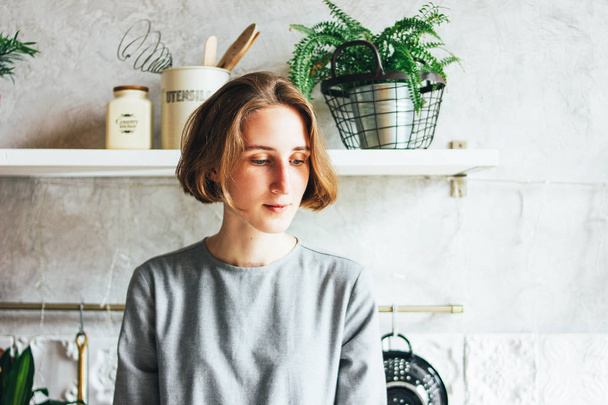 Giovane donna in abito grigio sulla cucina, interni scandinavi, vita lenta
 - Foto, immagini