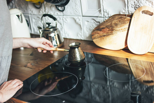 Νεαρή γυναίκα με γκρίζο φόρεμα φτιάχνοντας φυσικό μαύρο καφέ στο pot στην κουζίνα, πρωινή ρουτίνα - Φωτογραφία, εικόνα