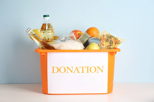 Box with donation food on table against light background - Photo, Image