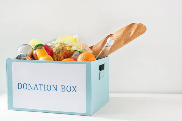 Caja con alimentos de donación sobre fondo blanco
 - Foto, imagen