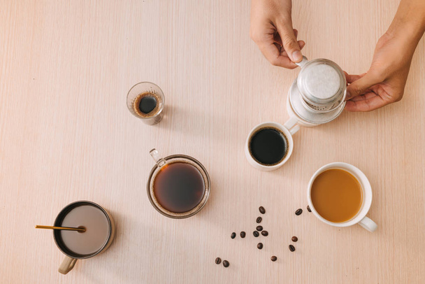 木製の背景にコーヒー豆とベトナムのフィンフィルターとコーヒーのカップ - 写真・画像