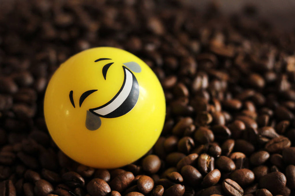 Positieve gele bal met een glimlach en koffiebonen, Goedemorgen. - Foto, afbeelding