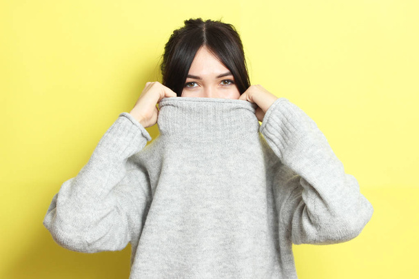 Beautiful girl in a warm cozy sweater on a colored background. - Фото, изображение