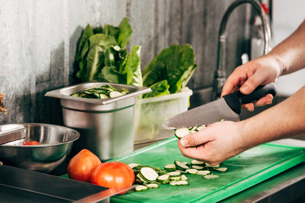 cropped view of cook cutting cucumbers on chopping board - Photo, Image
