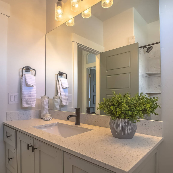 Čtvercové zrcadlo a ješitnost uvnitř koupelny s bílou stěnou a hnědou dřevěnou podlahou - Fotografie, Obrázek