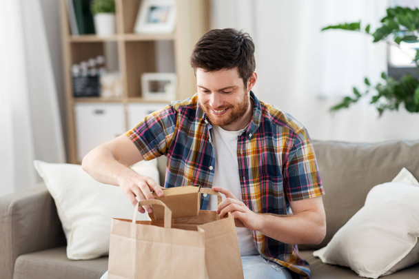 smiling man unpacking takeaway food at home - Valokuva, kuva