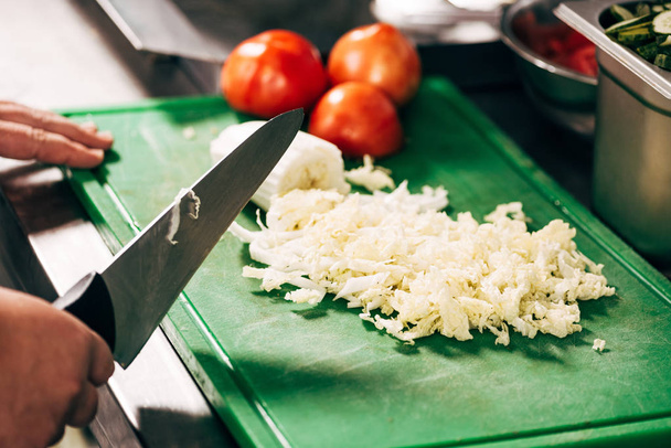 abgeschnittene Ansicht von Koch mit Messer in der Nähe Schneidebrett mit Salat und Tomaten - Foto, Bild