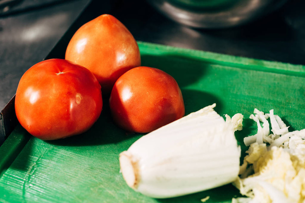 tomaattien ja leikatun salaatin valikoiva painopiste vihreällä leikkuulaudalla
 - Valokuva, kuva