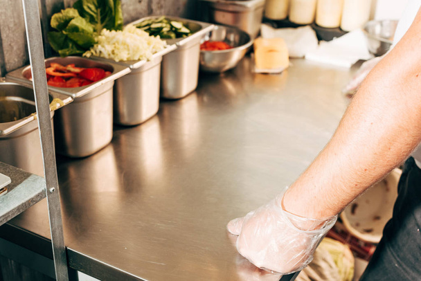oříznutý pohled na kuchaře v rukavičkách stojící blízko stolu s kontejnery - Fotografie, Obrázek