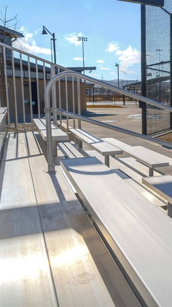 Verticaal gelaagde tribunes met metalen leuning op een sportveld bekeken op een zonnige dag - Foto, afbeelding