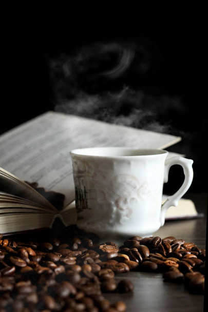 Черный кофе в белой чашке, кофейная фасоль и книга
 - Фото, изображение