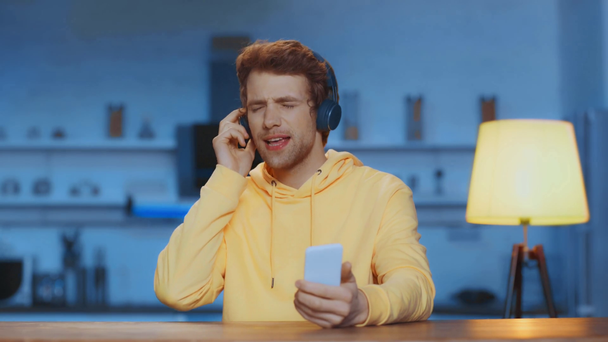 szczęśliwy człowiek za pomocą smartfona, taniec i słuchanie muzyki w słuchawkach - Materiał filmowy, wideo