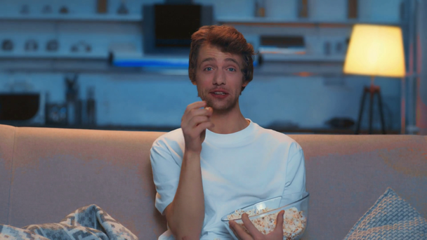 смеющийся человек ест попкорн во время просмотра комедии вечером
 - Кадры, видео