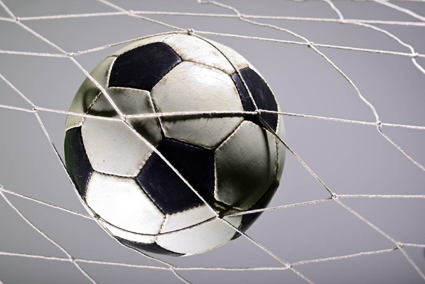 Anotación de gol, balón de fútbol en la red contra fondo gris
. - Foto, Imagen
