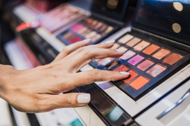 Рука женщины трогает красочный косметический порошок для макияжа
 - Фото, изображение