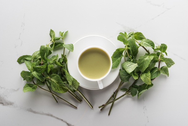 Top uitzicht op groene Matcha thee en Mint op witte tafel - Foto, afbeelding
