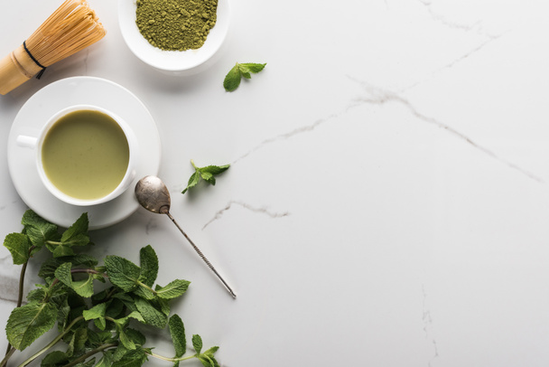 Blick von oben auf grünen Matcha-Tee mit Minze auf weißem Tisch  - Foto, Bild