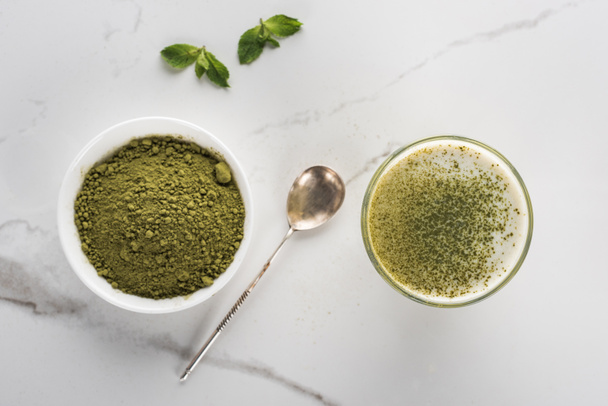 top view of matcha tea powder and drink in glass on white table - Foto, immagini