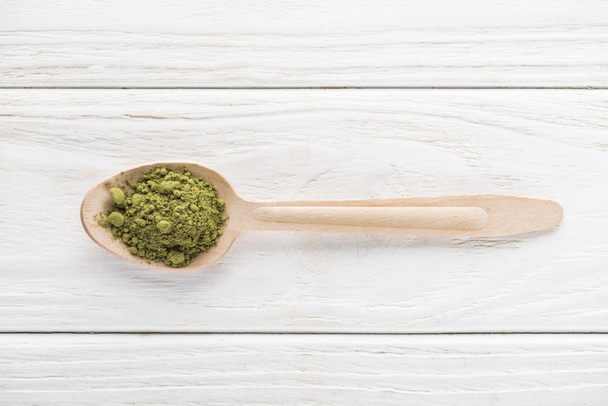 top view of wooden spoon with powder of green matcha tea  - Фото, изображение