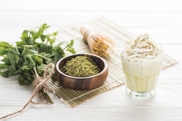 matcha tea with whipped cream on bamboo mat with powder, mint and whisk - Φωτογραφία, εικόνα