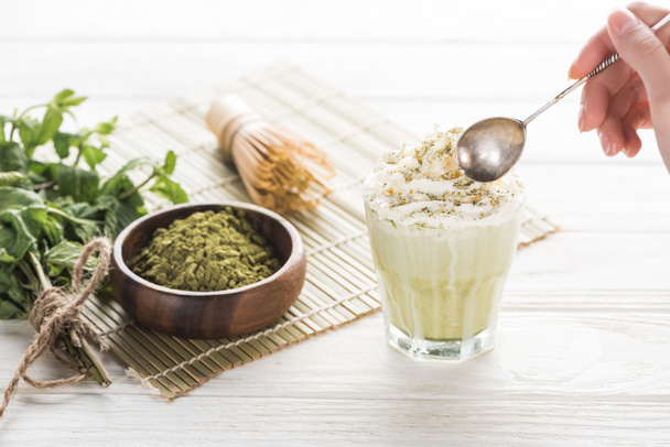 cropped view of woman with matcha matcha tea in glass with whipped cream - Photo, Image