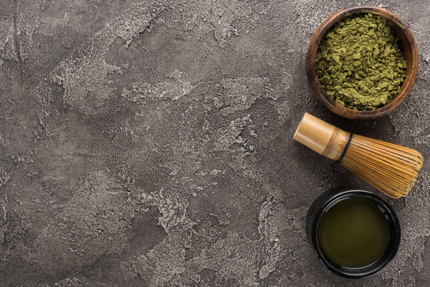 top view of matcha green tea and whisk on dark stone table - Фото, изображение