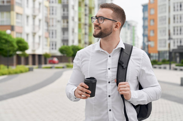 Positive student standing with backpack and coffee cup. - 写真・画像