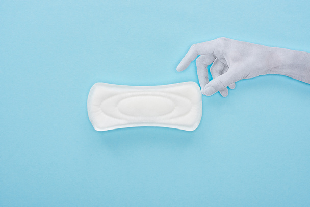 top view of white paper hand and cotton sanitary towel on blue background - Valokuva, kuva