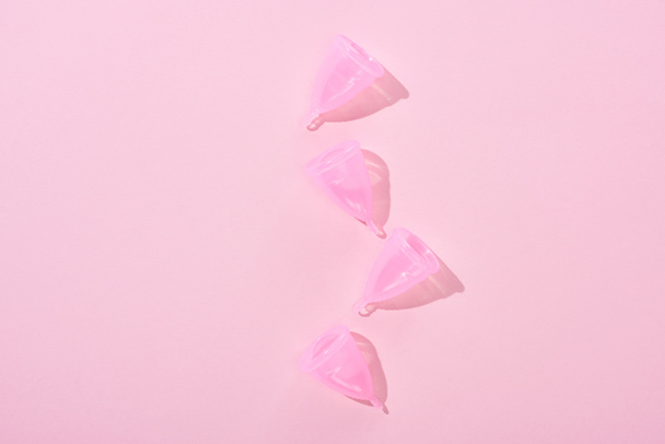 top view of pink plastic menstrual cups on pink background - Φωτογραφία, εικόνα
