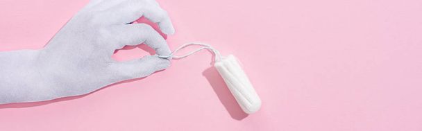 top view of white paper hand holding cotton tampon on pink background, panoramic shot - Fotó, kép