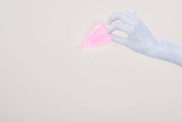 vue du dessus de la main en papier blanc tenant une coupe menstruelle en plastique rose isolée sur gris
 - Photo, image